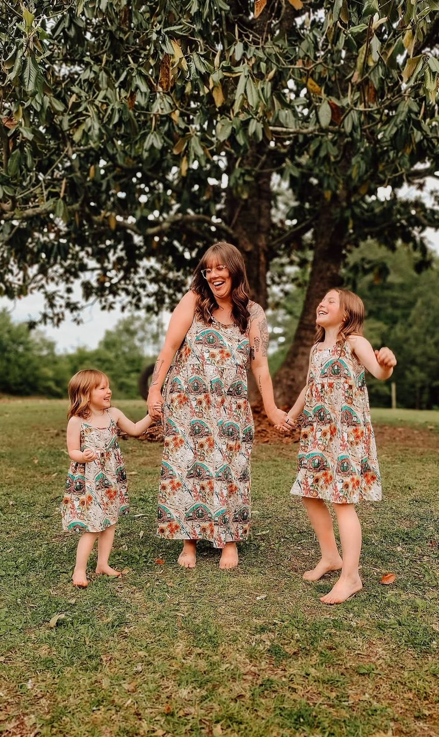 A mother and two girls laughing together in matching Shire dresses